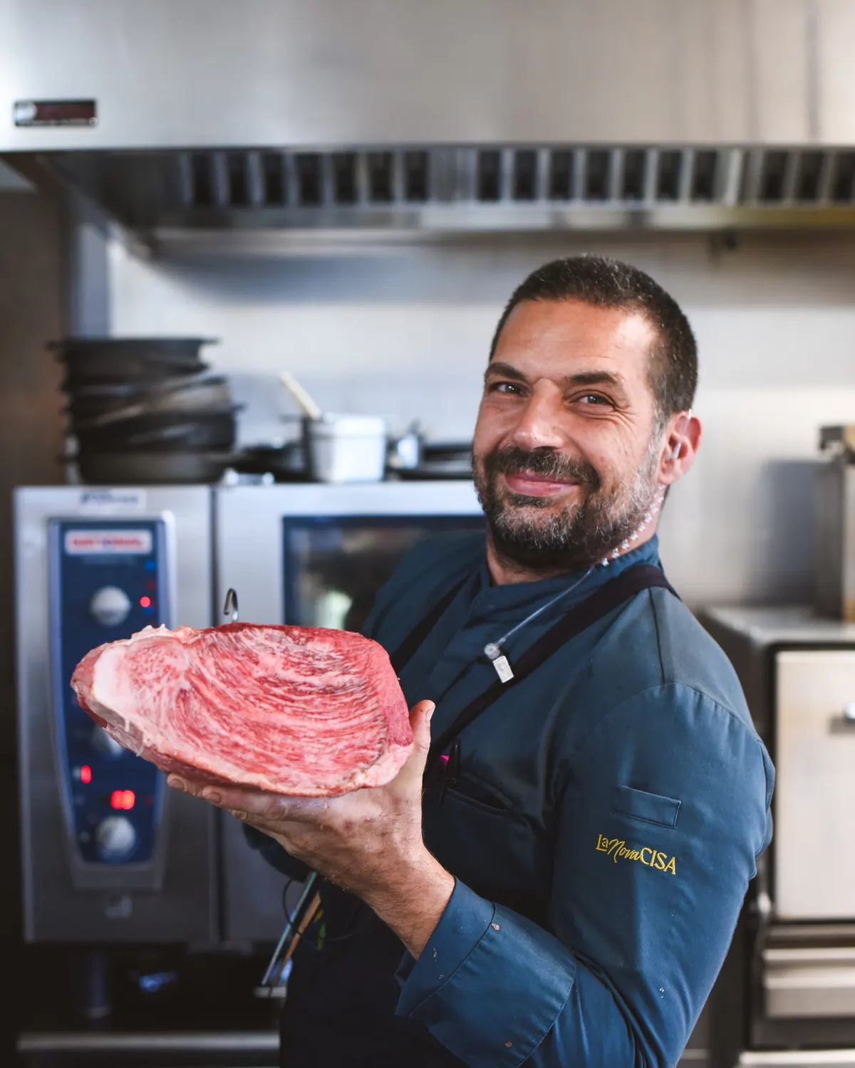 La Nova Cisa's chef holding a cut of beef in the kitchen